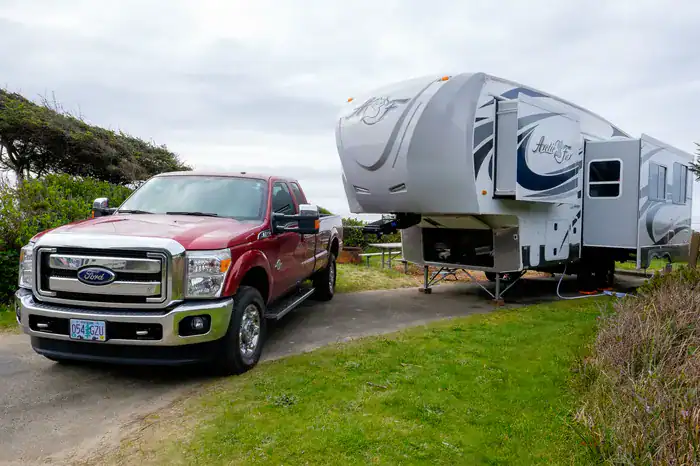 A Fifth Wheel with a truck parked up next to it.