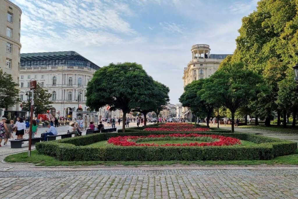 Clean and well-kept street with gardens, trees and historic buildings in Warsaw city centre.