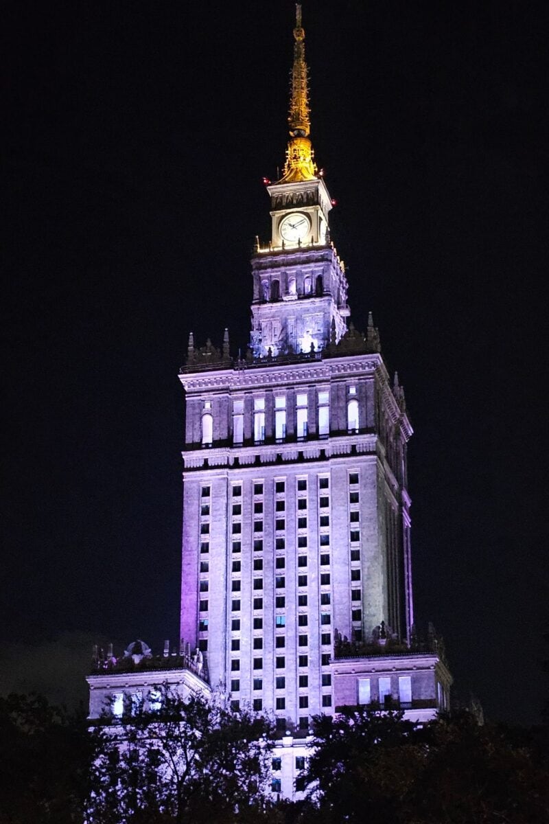 Palace of Culture and Science lit up at night in Warsaw city centre.